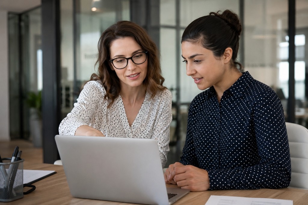 Two professionals reviewing opportunities together on a laptop in a modern office